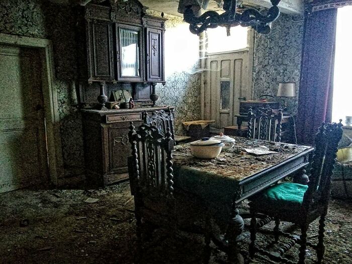 Urban explorers uncover an unexpected, antique dining room, covered in dust and debris, within an abandoned house.