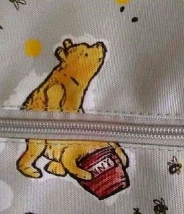 Winnie the Pooh split by a zipper, creating an awkward design fail on a bag.