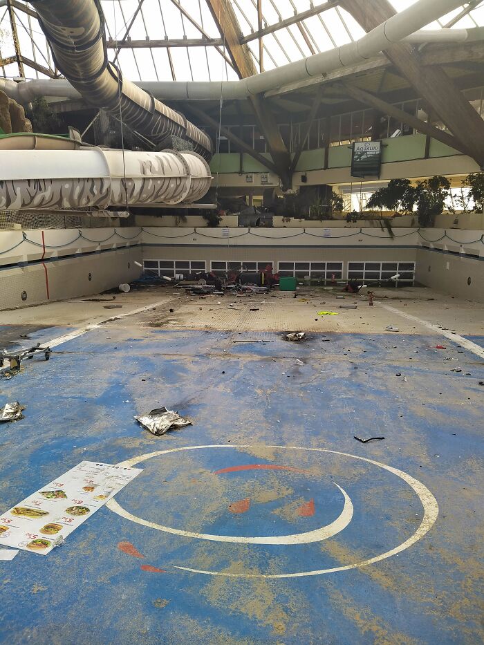 A derelict indoor swimming pool area with water slides and debris, an unexpected find for urban explorers.