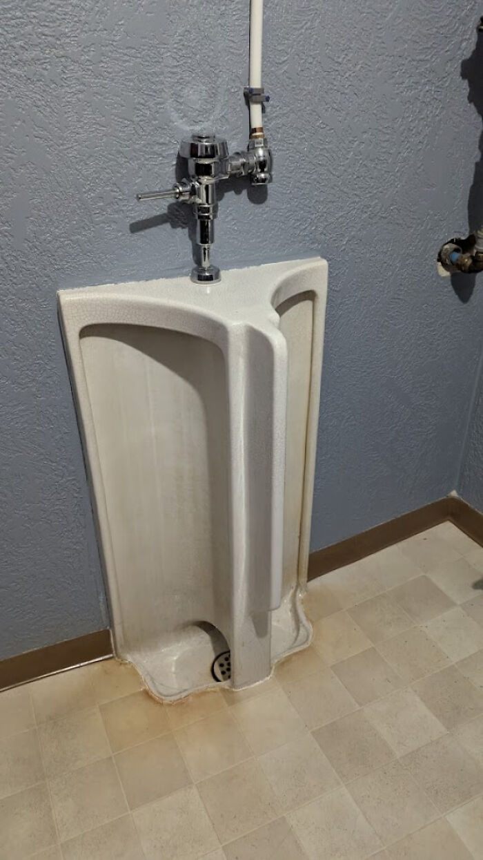 A urinal with a baffling triangular design, a design fail that someone should be held responsible for.