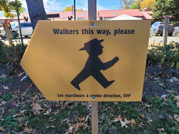 A hilariously awful design fail: a yellow sign with a walker symbol pointing in an odd direction for pedestrians.