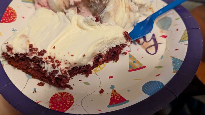 A hilariously awful design fail birthday cake with red velvet and white frosting on a party plate with a blue fork.