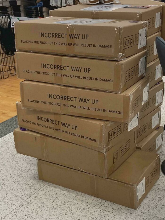 A hilariously awful design fail stack of cardboard boxes with the warning INCORRECT WAY UP and an arrow pointing up.