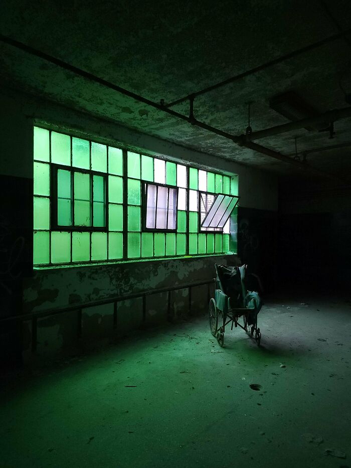 Urban explorers found a wheelchair in a dimly lit room with green windows.