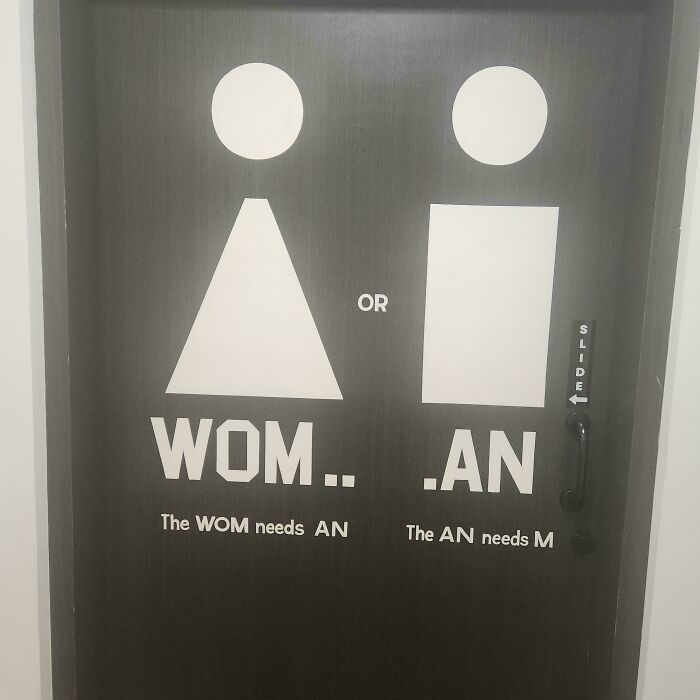 A black restroom door with confusing Wom.. .An text and icons. A hilarious design fail.