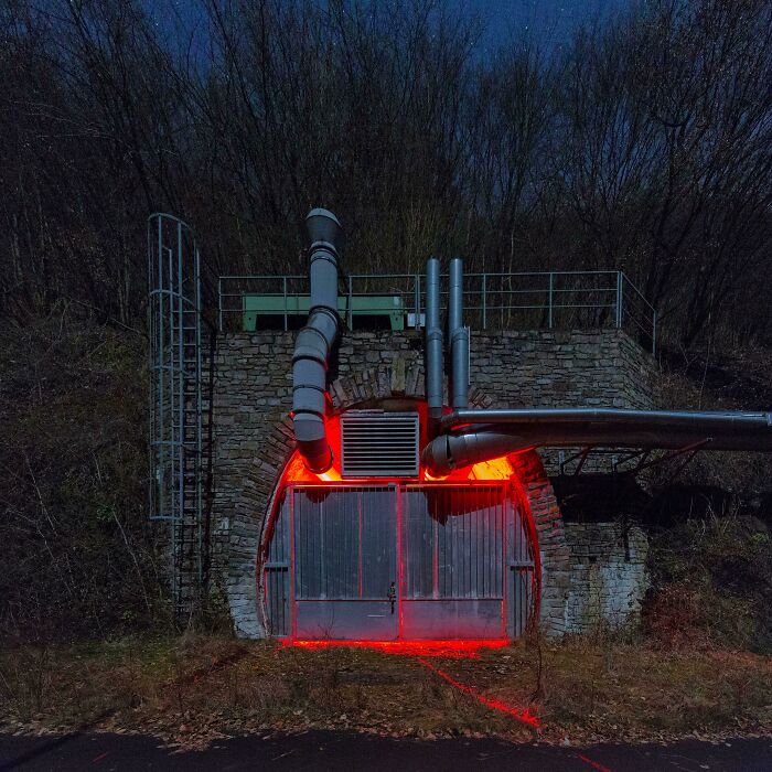 A concrete and brick structure with red glowing lights and pipes, an unexpected find for urban explorers.