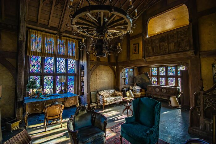 An old, ornate room with stained glass windows and a large wooden chandelier, an unexpected find for urban explorers.