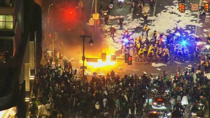 An aerial view of a riot scene with a fire in the middle of a street, showcasing different photos of USA.