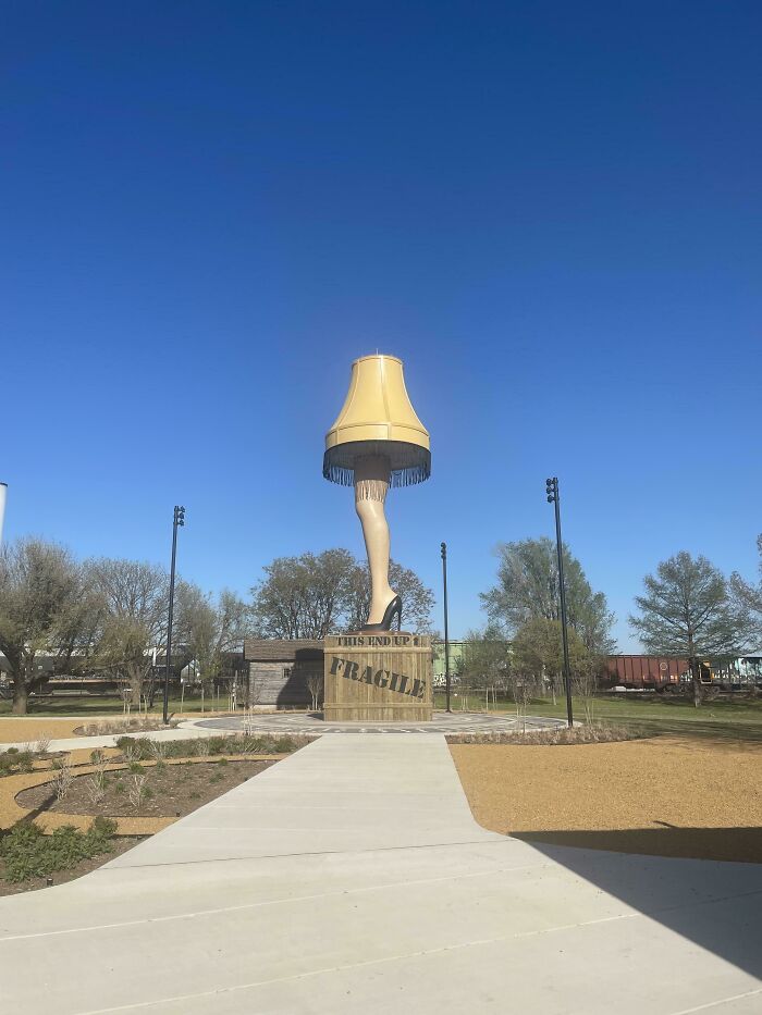 A giant leg lamp sculpture, like the one from the movie A Christmas Story, stands tall against a blue sky, showcasing different photos of the USA.