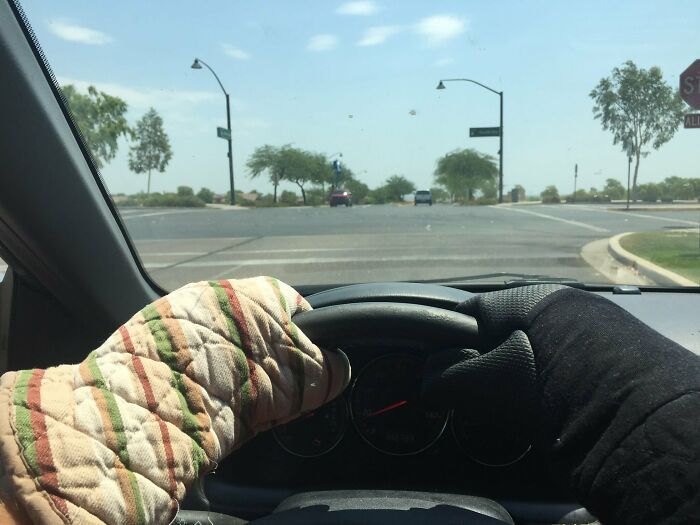 Photos of the USA: Hands wearing oven mitts gripping a steering wheel, driving on a sunny day.