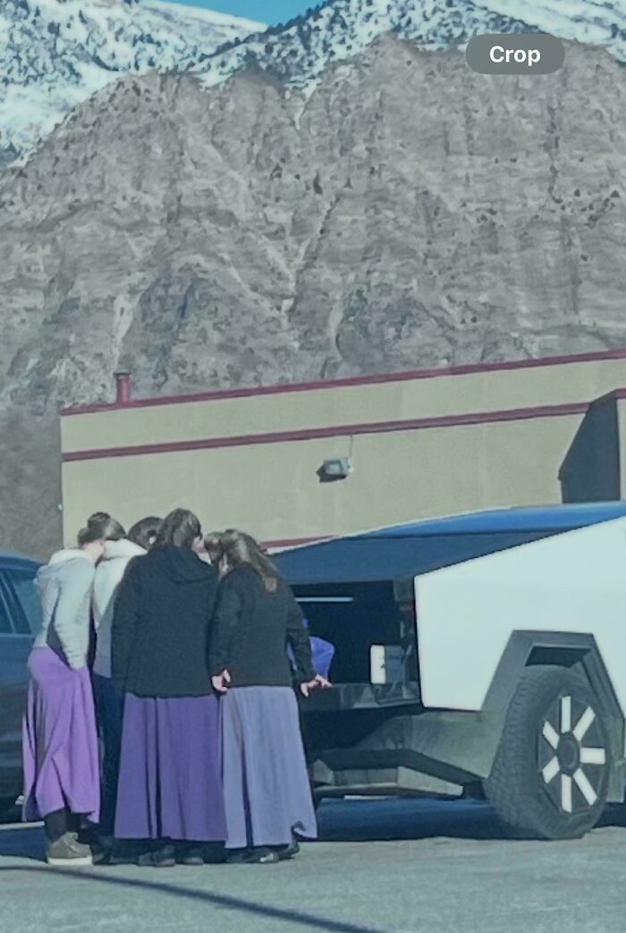 Photos of the USA: People in long skirts by a white futuristic vehicle with a snowy mountain background.