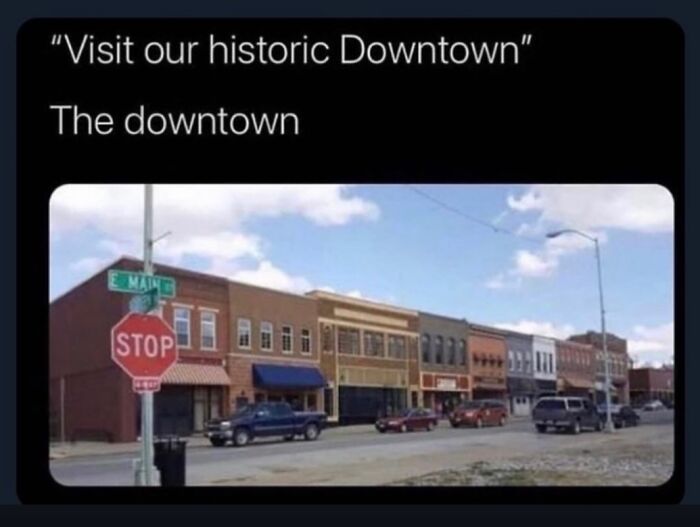 A quaint historic downtown street with various small businesses, parked cars, and a stop sign in the USA.