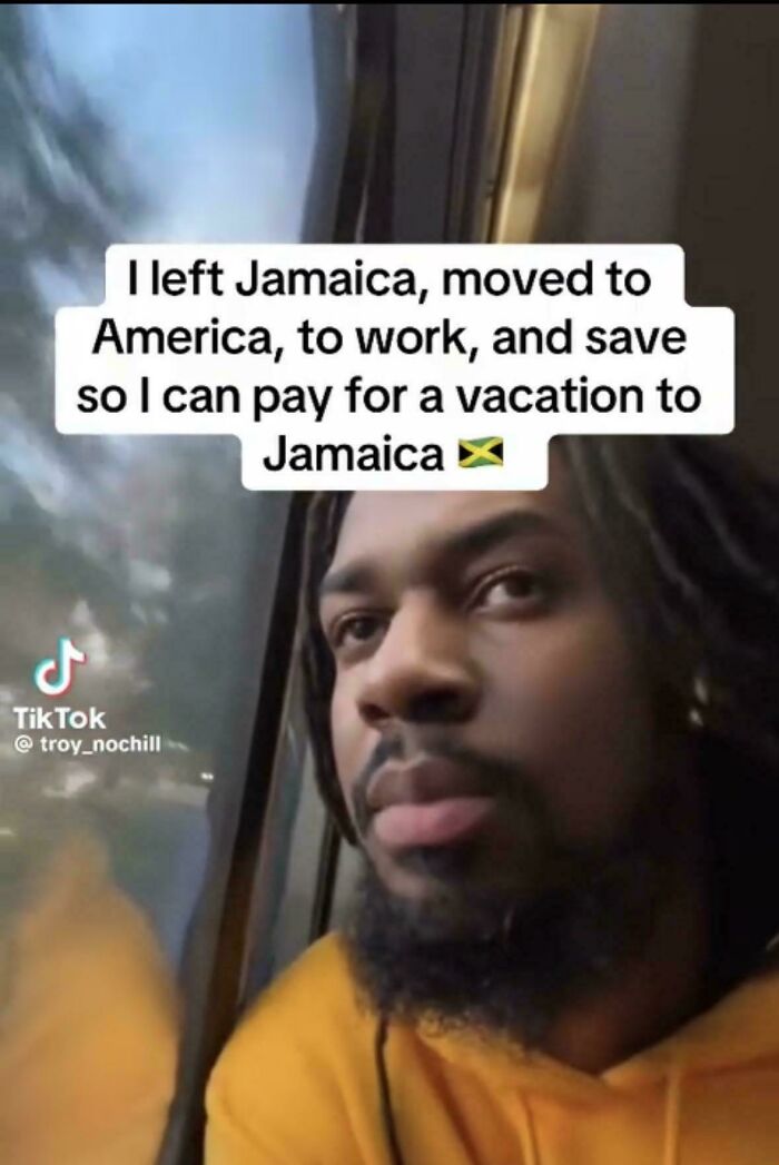 A man looking out a window, reflecting on the funny and confusing irony of leaving Jamaica to work in America for a Jamaican vacation.