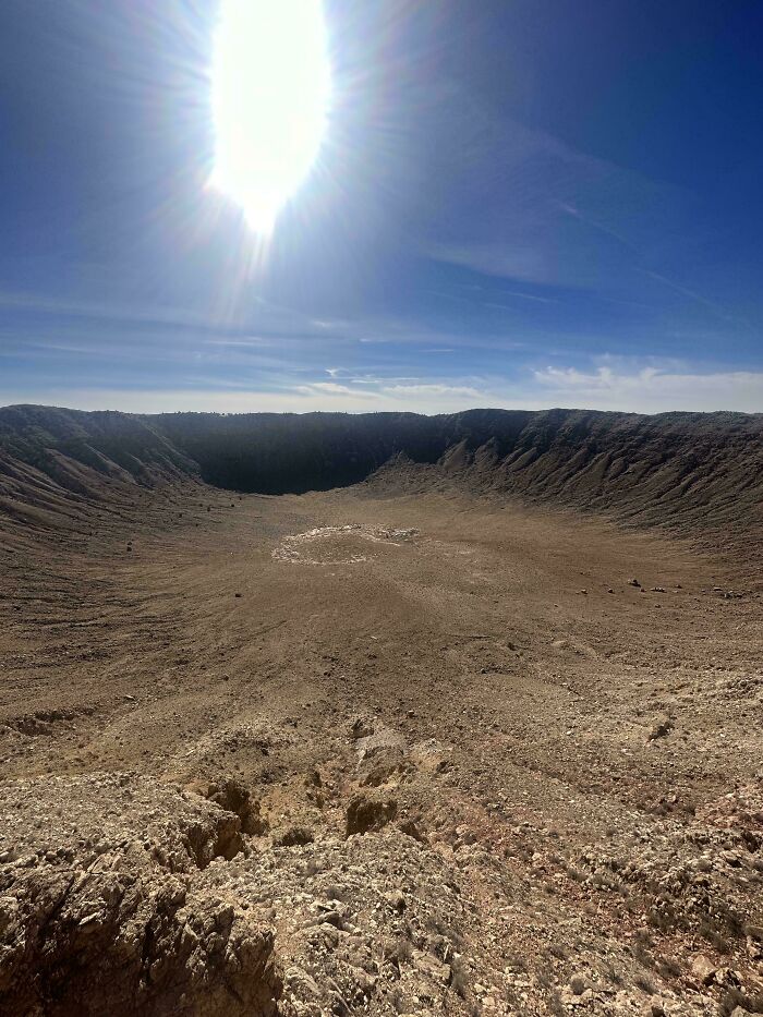 A vast, desolate meteor crater under a bright sun, highlighting the wildly different photos of the USA's terrain.