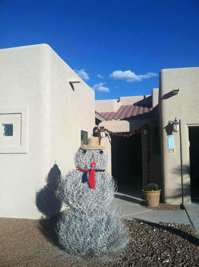 A snowman made of tumbleweeds in front of adobe buildings, a fascinating and different photo of the USA.