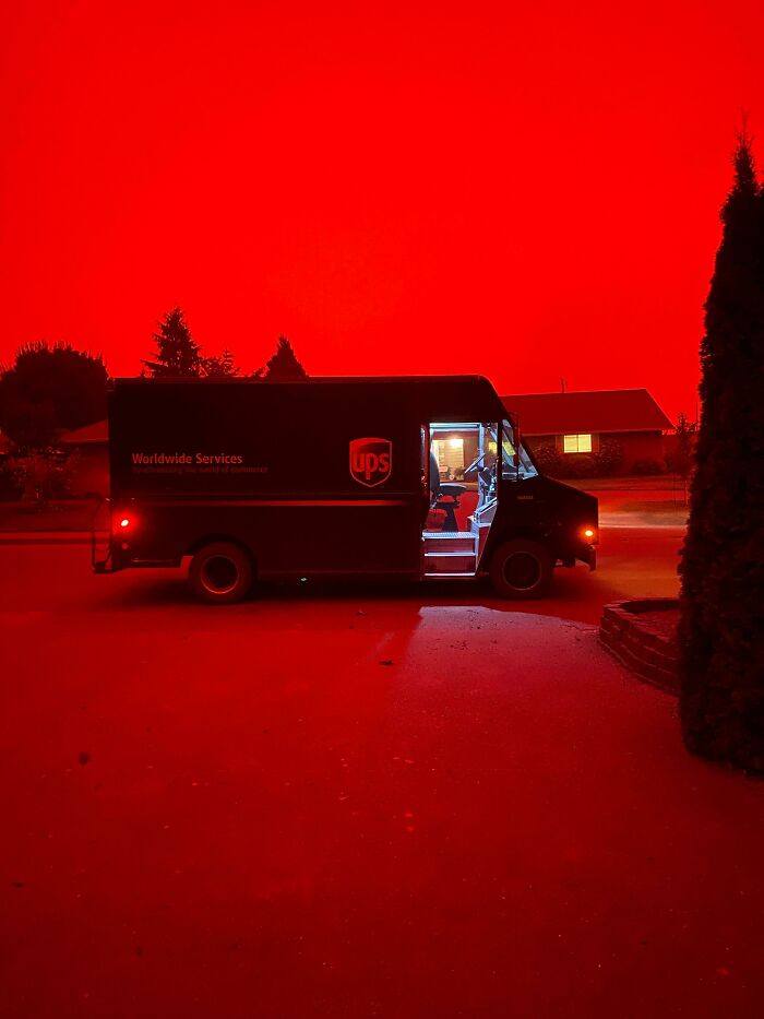 A UPS truck in a neighborhood under a dramatically red sky, capturing a fascinating and different USA scene.