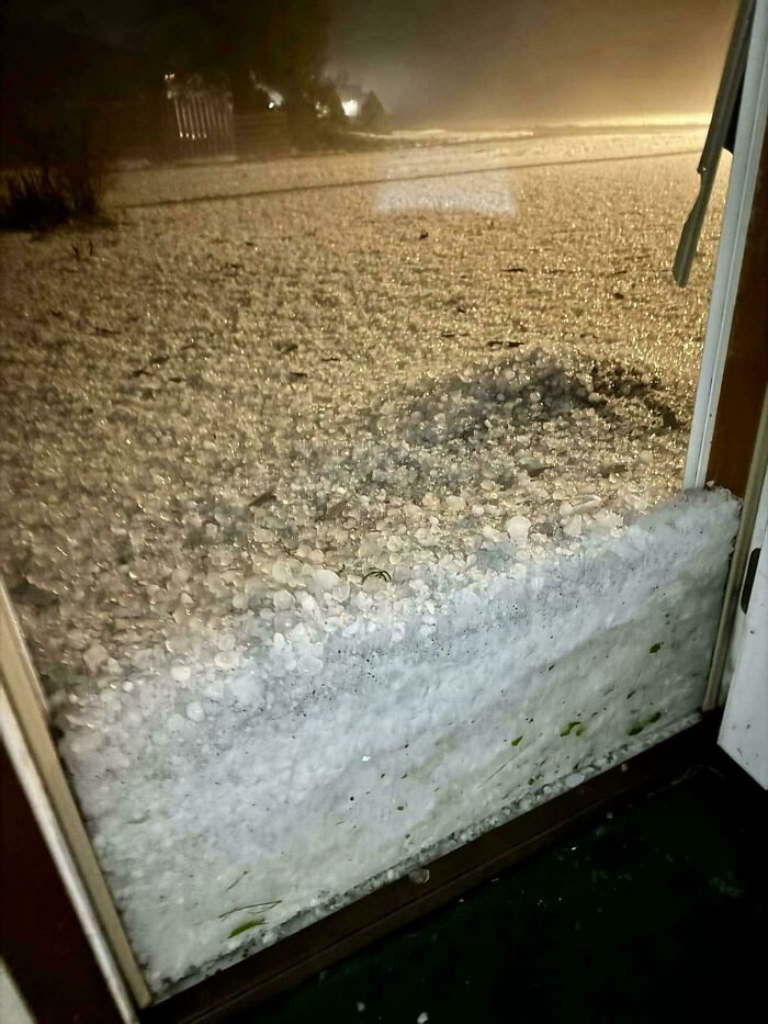 A door blocked by a huge pile of hail from a USA storm, showing the wildly different weather in the country.