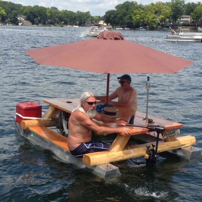 Two men on a floating picnic table with an umbrella on a lake, a wildly different photo of the USA.