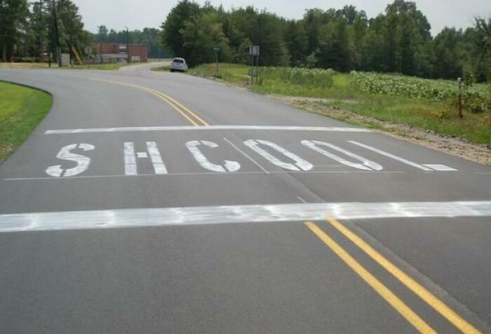 A road with the word S H C O O L painted, one of the wildly different photos of the USA.
