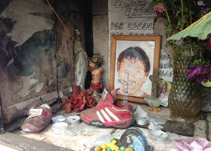 A makeshift memorial with a photo, shoes, and candles, revealing a horrific fate for a disappeared man.