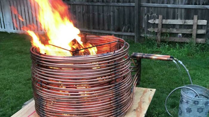 A copper coil fire pit heating water, a clever solution for outdoor comfort made from random junk.