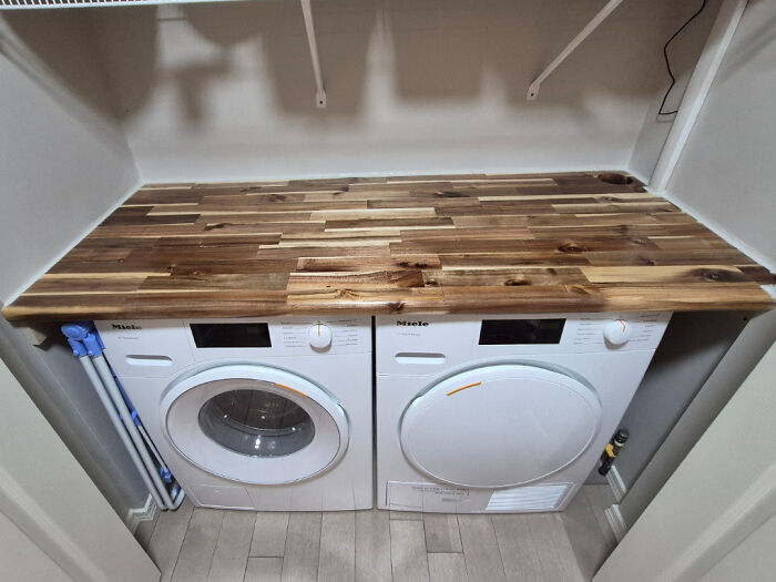 Laundry room home improvement project with a new wooden countertop above a washer and dryer, optimizing space.
