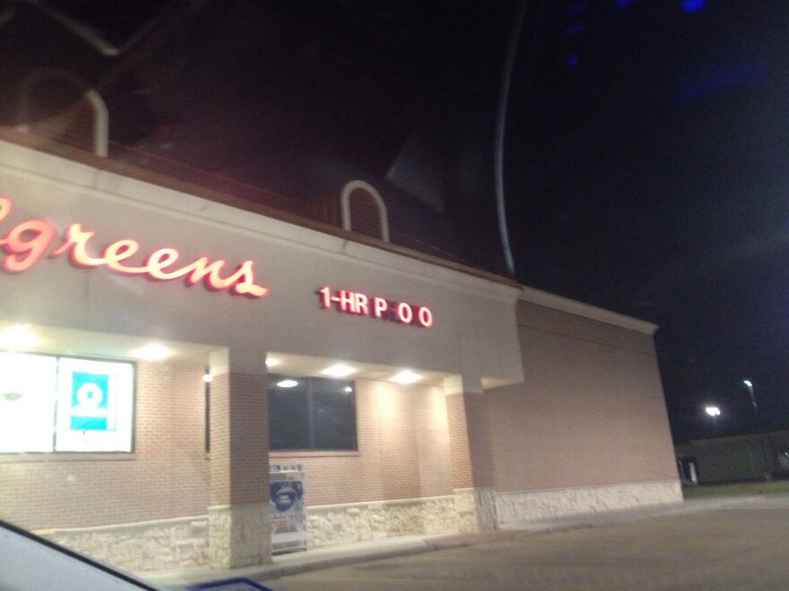 A Walgreens store sign at night, with a humorous light malfunction displaying 1-HR P*O, an amusing thing.