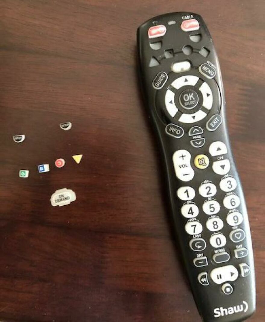 A TV remote control with several buttons popped off and scattered nearby, a mildly amusing inconvenience.