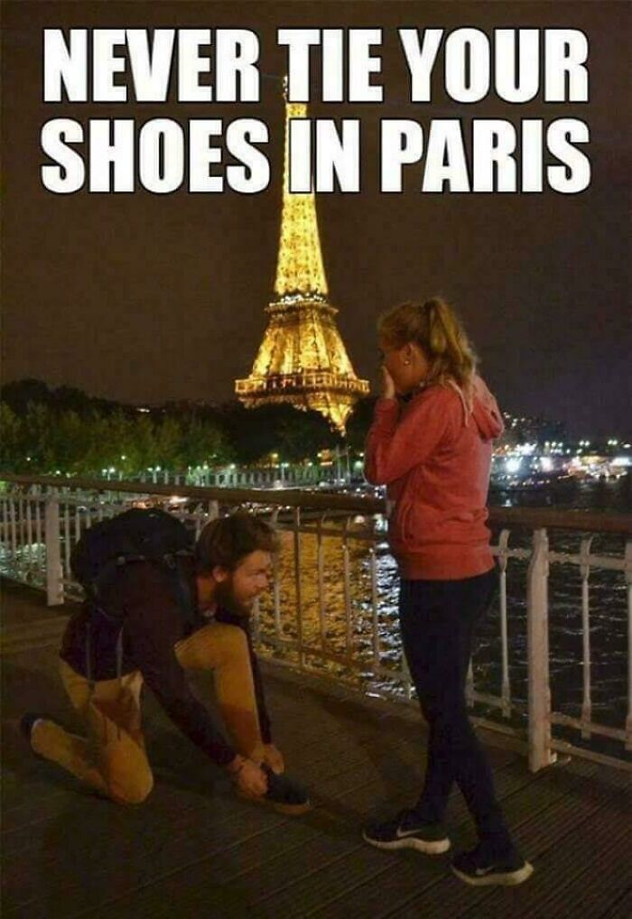 A man tying a woman's shoe in front of the Eiffel Tower, a funny ancient meme.