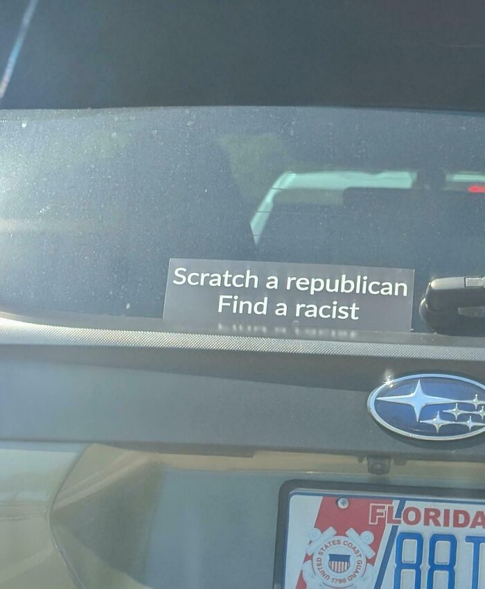 A car's back window with a funny bumper sticker reads, Scratch a republican, Find a racist. This unfiltered bumper sticker makes a double take.