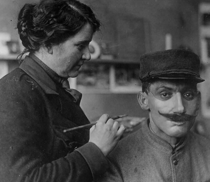 An intriguing historical photo of a woman applying makeup to a man's face, a glimpse into past daily life.