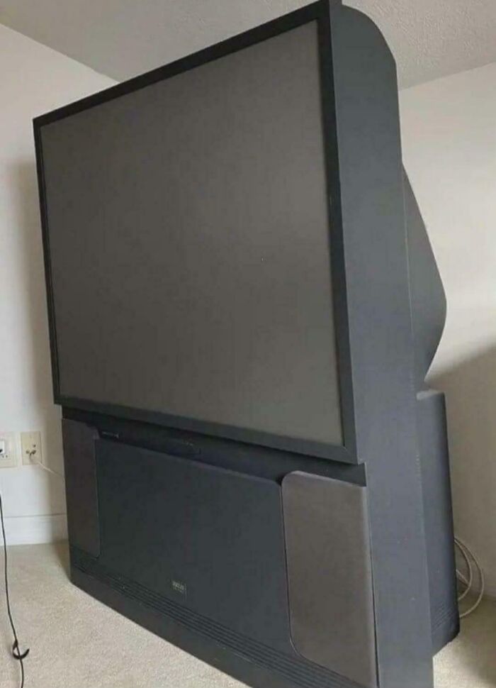 A large, old projection TV in a room, a historical photo of past technology.