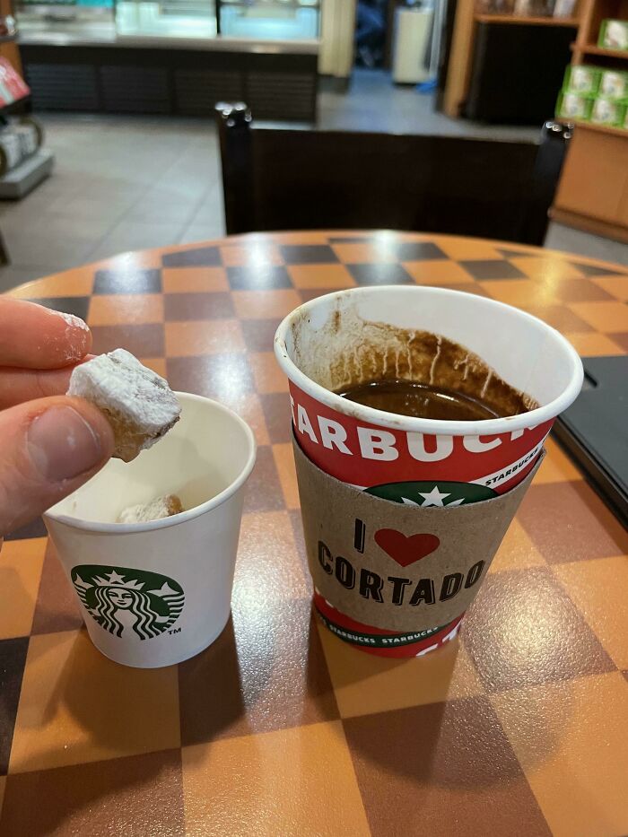 Hand holding a powdered donut over a small cup next to a Starbucks cup with I Love Cortado, a simple business idea.