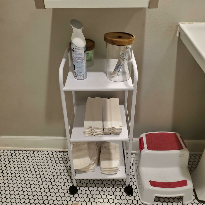 White rolling cart with diapers, wipes, and air freshener, a simple and genius solution for parents.
