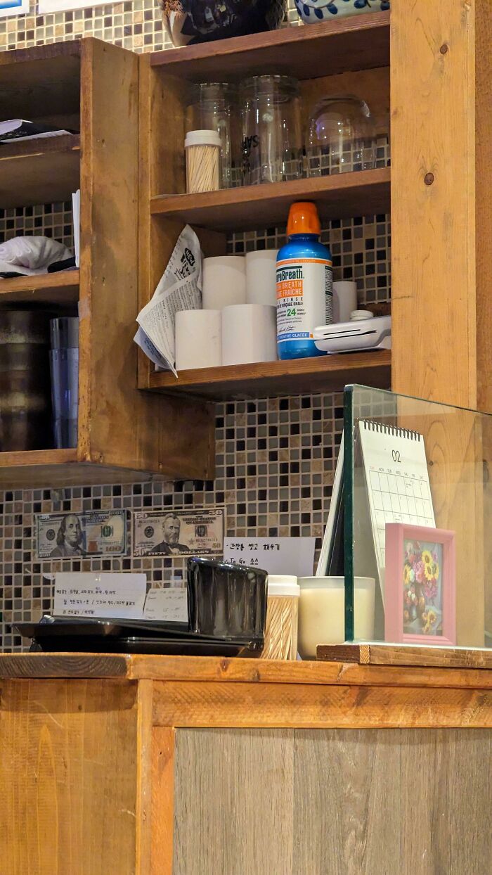 A surprisingly simple and genius idea, a small wooden shelf with various items, including dollar bills.