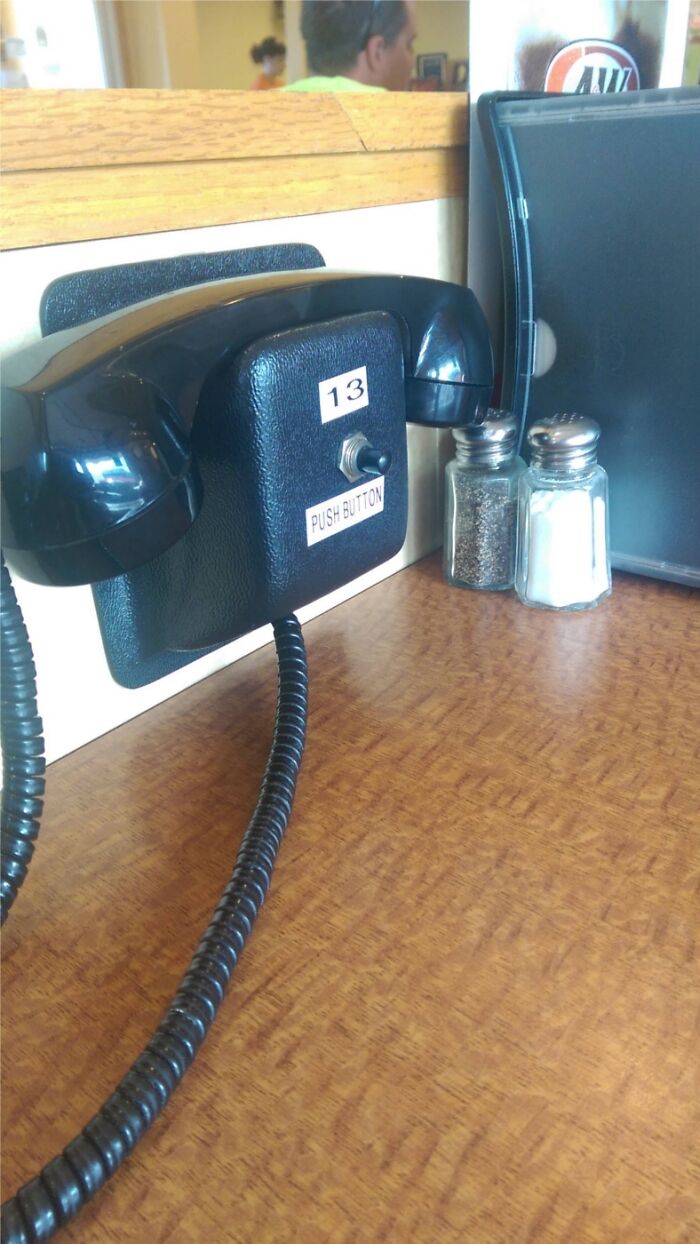 A black telephone with a 'push button' switch on a restaurant table, a simple, genius idea for service.