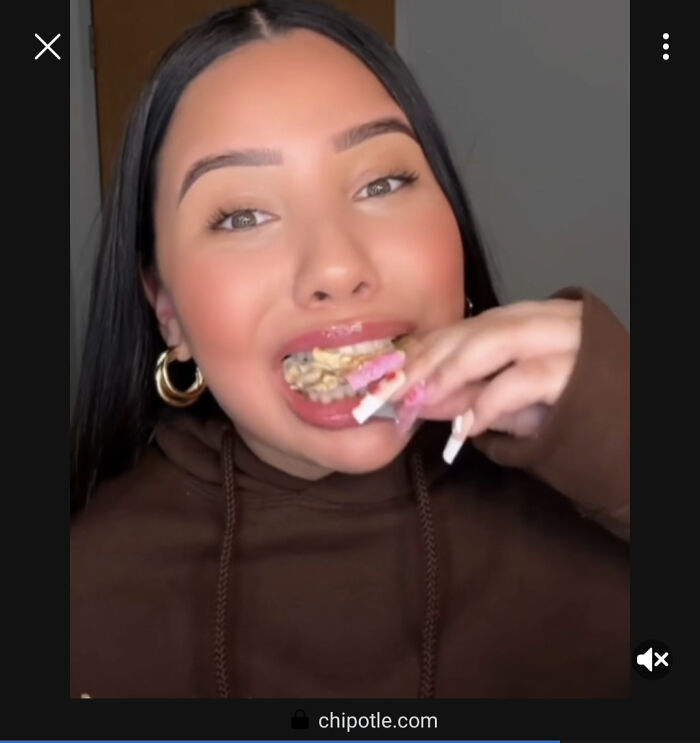 A woman with long dark hair and gold hoop earrings eating food, an example of a commercial.