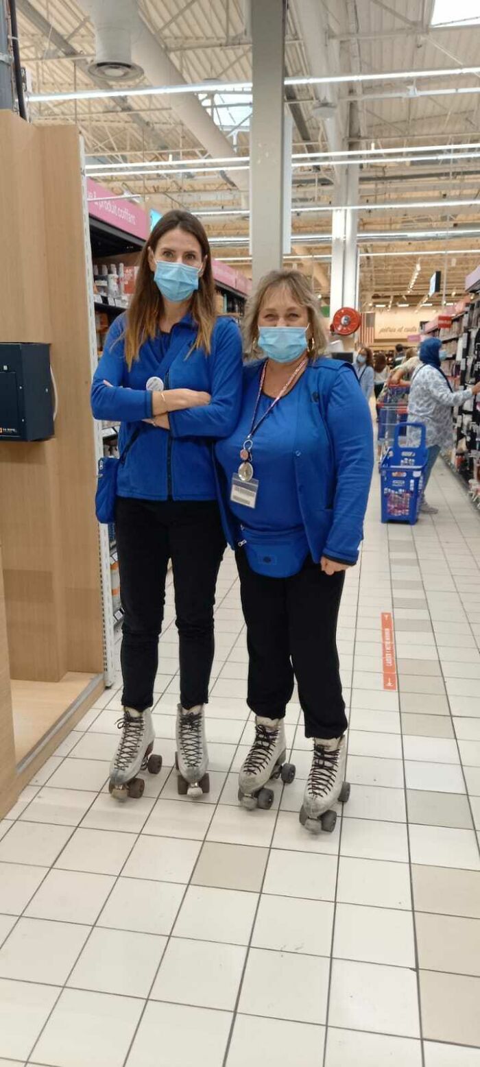 Two women wearing masks and roller skates in a supermarket aisle, demonstrating a simple and genius idea for efficient work.