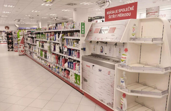A supermarket aisle with a Genius Idea for solving Everyday Problems, featuring a refill station for detergents and various products.