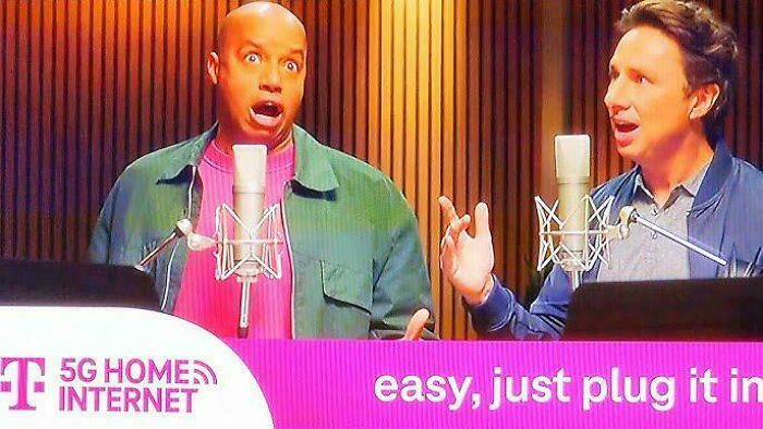 Two men, one with wide eyes, behind microphones in a studio, discussing commercials.