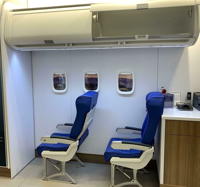 Two airline seats and overhead compartments in a retail display, a genius idea to solve an everyday problem.