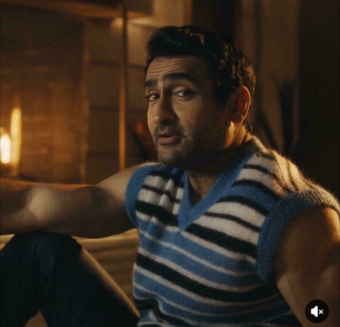 A man with a subtle smirk, wearing a striped blue and white sweater vest, appearing in a commercial.