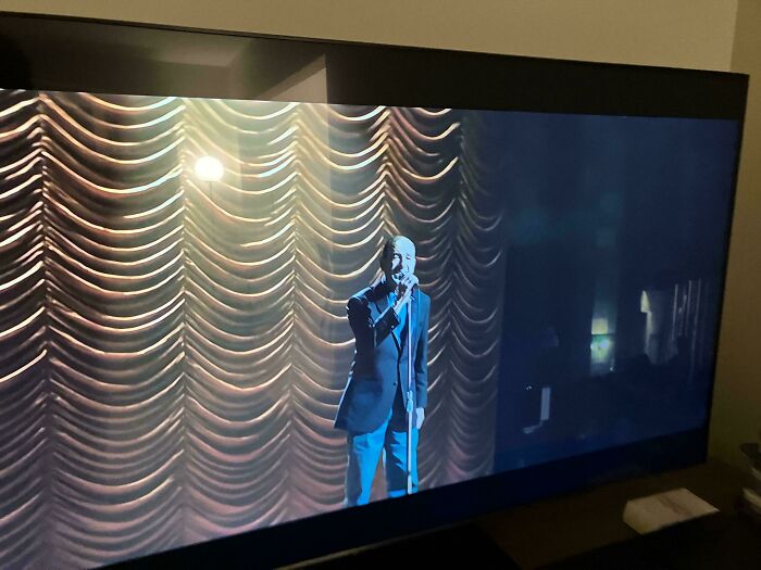 A man singing on stage with a spotlight on him, displayed on a TV screen, from commercials people can't stand.