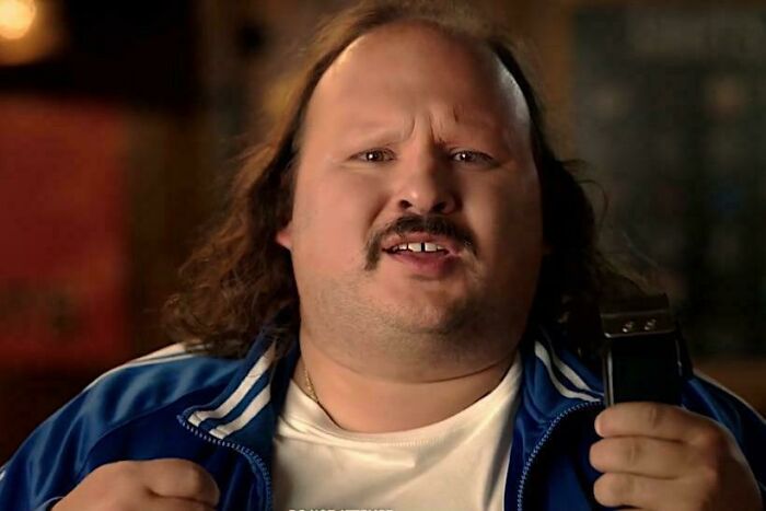 A man with a mustache and long hair from commercials people cant stand, holding a grooming tool.