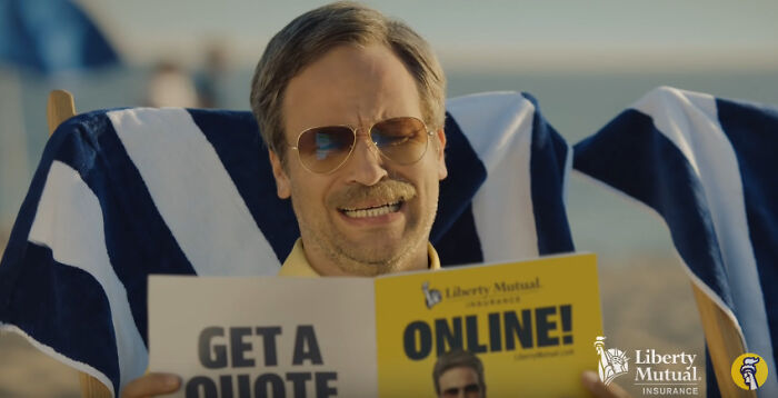 A man on a beach chair looks distressed while holding Liberty Mutual Insurance flyers, portraying a dislike for commercials.