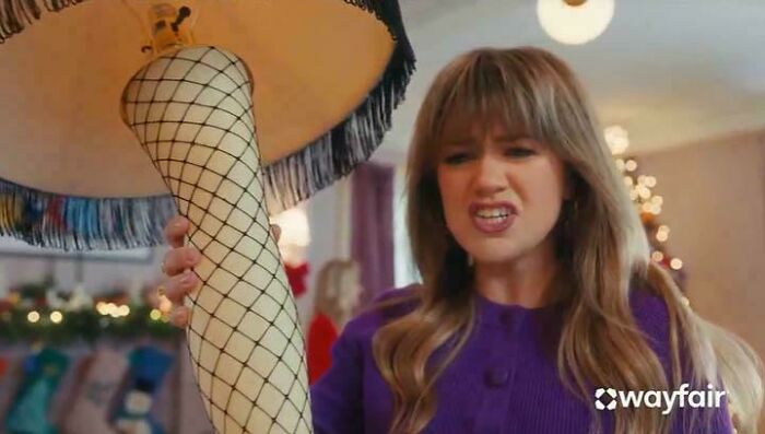 A woman looking disgusted while holding a leg lamp from a commercial people can't stand.