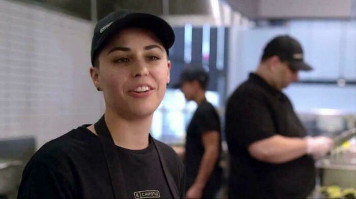 A restaurant worker in a black uniform smiles, representing the commercials people cant stand.