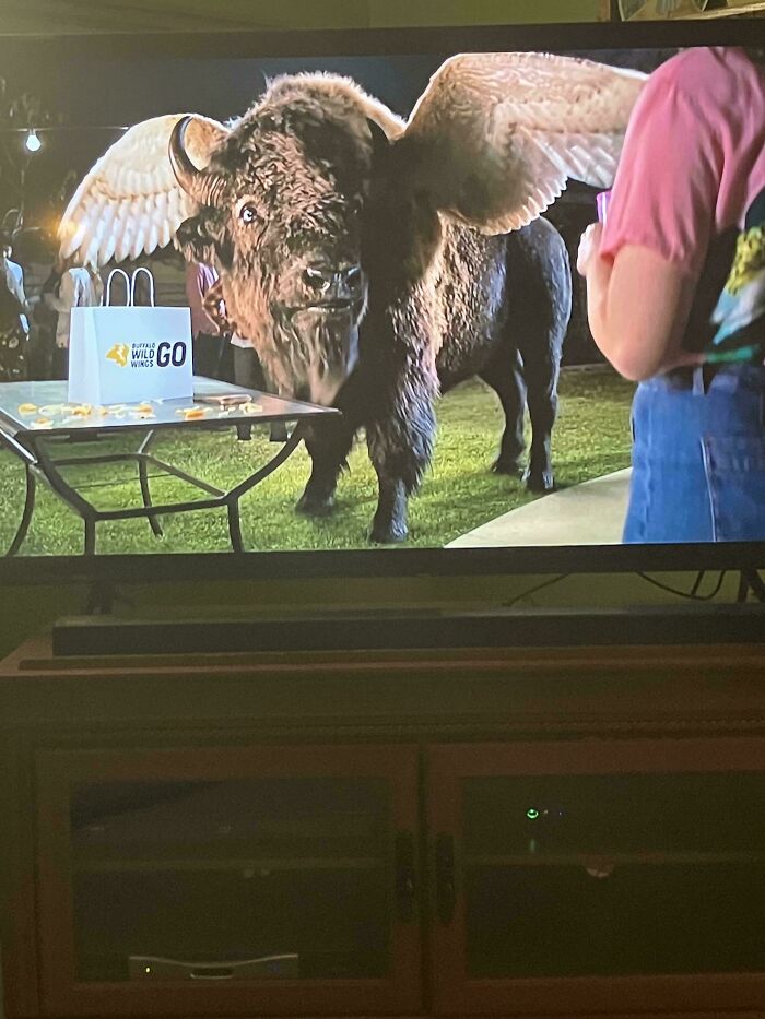 A large bison with wings standing next to a table with Buffalo Wild Wings bags, illustrating commercials people can't stand.