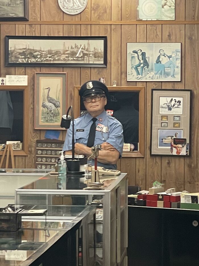A man in a uniform standing behind a counter in a shop, showcasing a simple business idea.