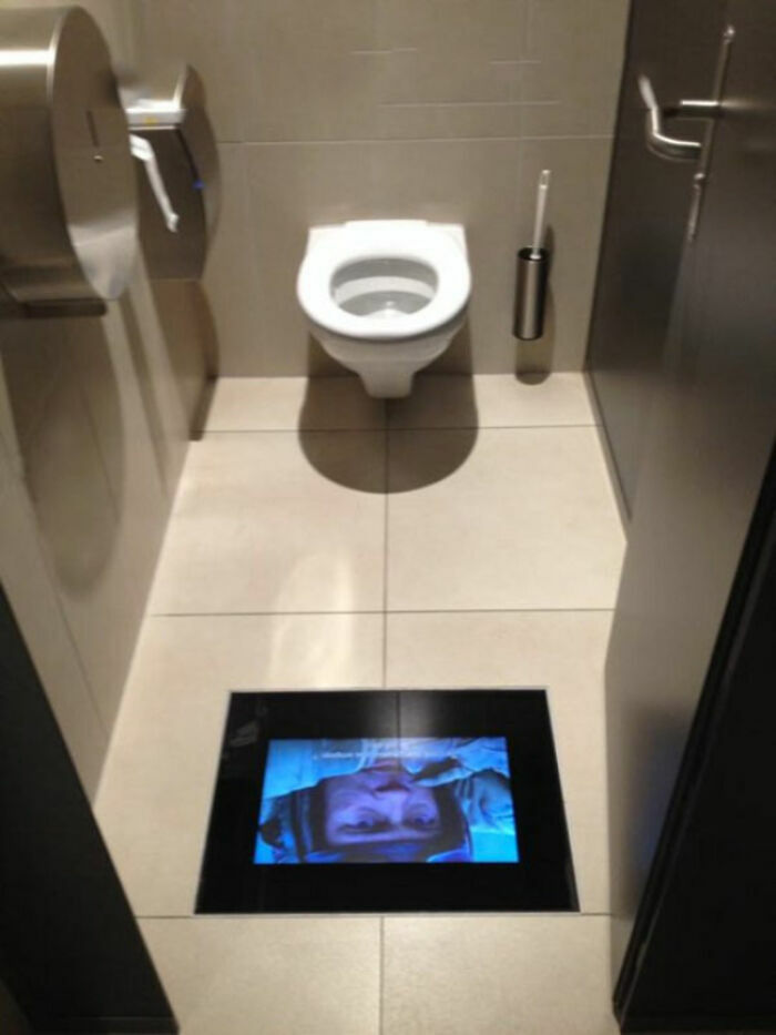 A toilet with a screen on the floor displaying a face, one of the many simple and genius ideas solving everyday problems.